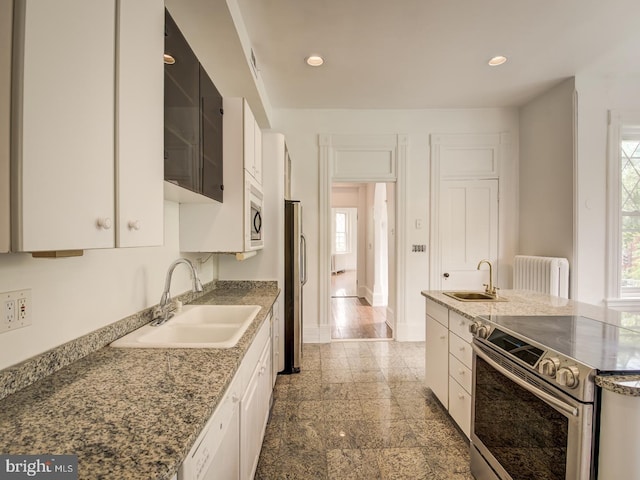 kitchen featuring white cabinets, radiator, sink, and appliances with stainless steel finishes