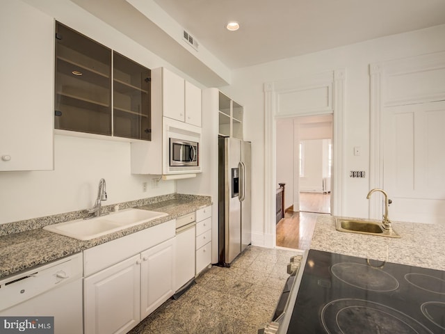 kitchen with light stone countertops, appliances with stainless steel finishes, white cabinetry, and sink