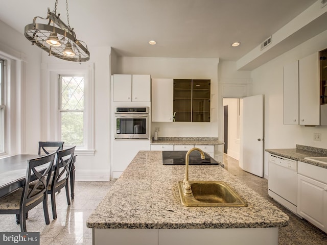 kitchen featuring stainless steel oven, white dishwasher, sink, an island with sink, and white cabinetry