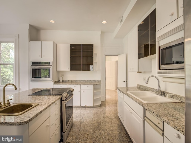 kitchen with sink, white cabinets, a kitchen island, and appliances with stainless steel finishes