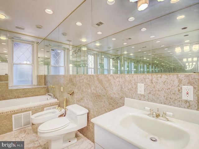 bathroom featuring vanity, tiled bath, toilet, and a bidet