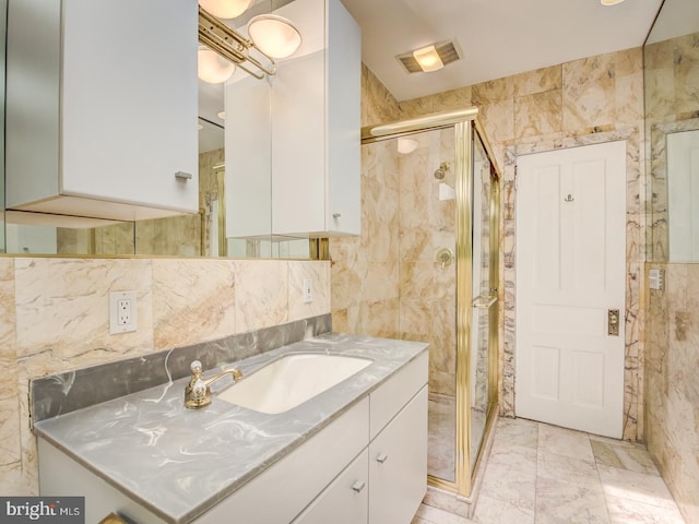 bathroom featuring a shower with door, vanity, and tile walls