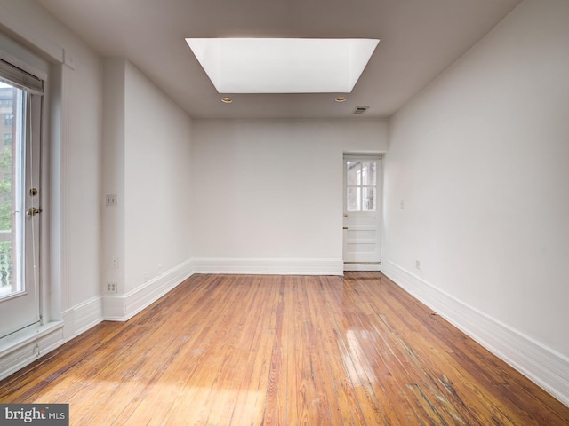 unfurnished room featuring light wood-type flooring, a wealth of natural light, and a skylight