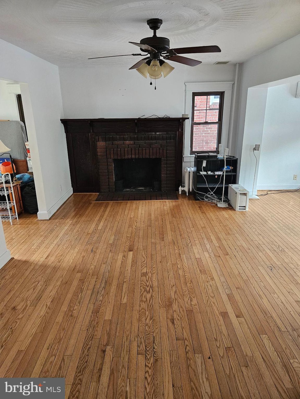 unfurnished living room with light hardwood / wood-style flooring, ceiling fan, and a fireplace