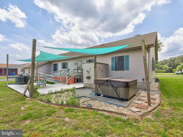 rear view of property featuring a deck, a hot tub, a patio area, and a lawn