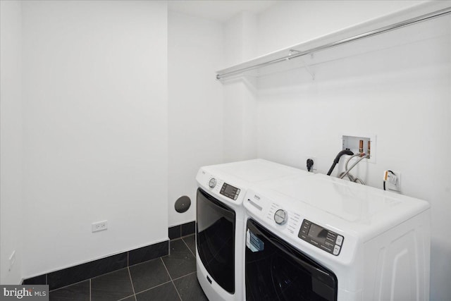 laundry area featuring electric dryer hookup, dark tile flooring, washer hookup, and washing machine and clothes dryer