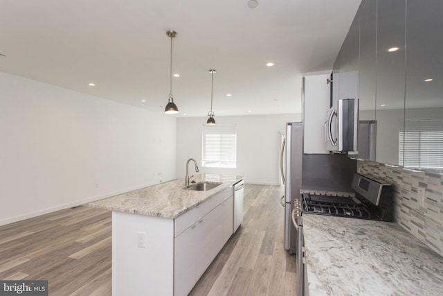 kitchen featuring pendant lighting, a kitchen island with sink, light hardwood / wood-style flooring, stainless steel appliances, and sink