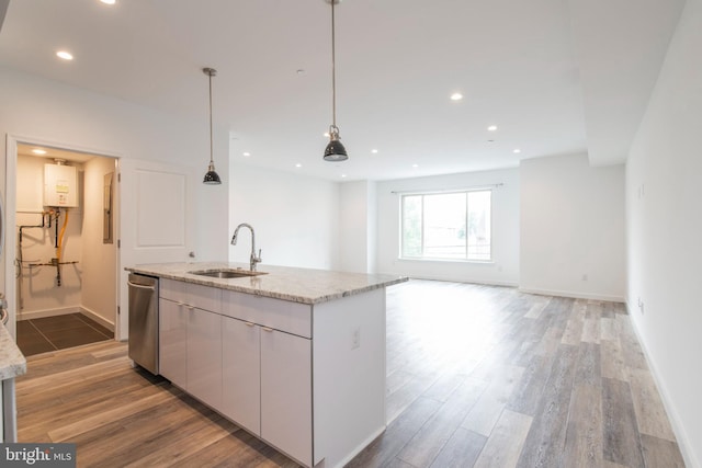 kitchen with hanging light fixtures, sink, hardwood / wood-style flooring, and a kitchen island with sink