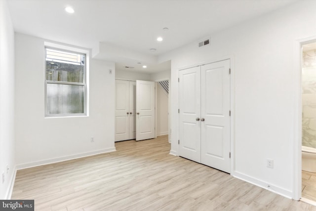 unfurnished bedroom with connected bathroom and light hardwood / wood-style flooring