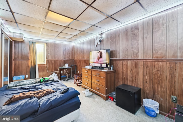 bedroom featuring wooden walls, light carpet, and a paneled ceiling