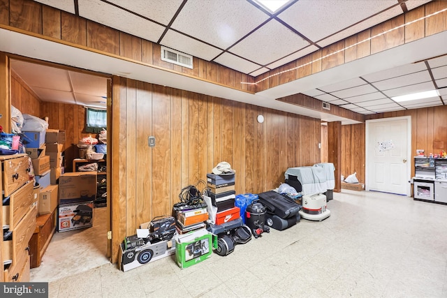 interior space featuring tile flooring, a paneled ceiling, and wooden walls