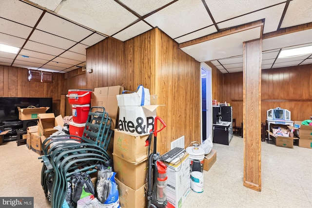 basement with wooden walls, carpet, and a paneled ceiling