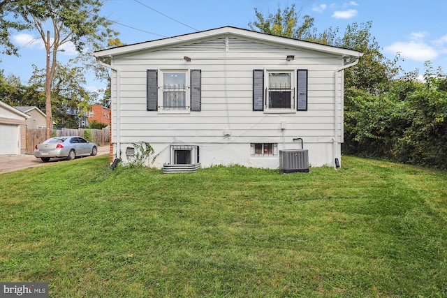 rear view of house with central air condition unit and a lawn