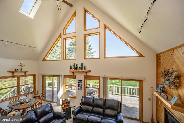 living room with a skylight, wood walls, track lighting, and high vaulted ceiling