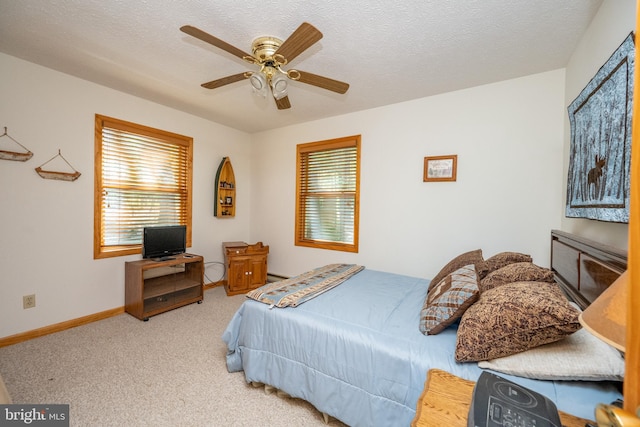 carpeted bedroom featuring ceiling fan and a textured ceiling