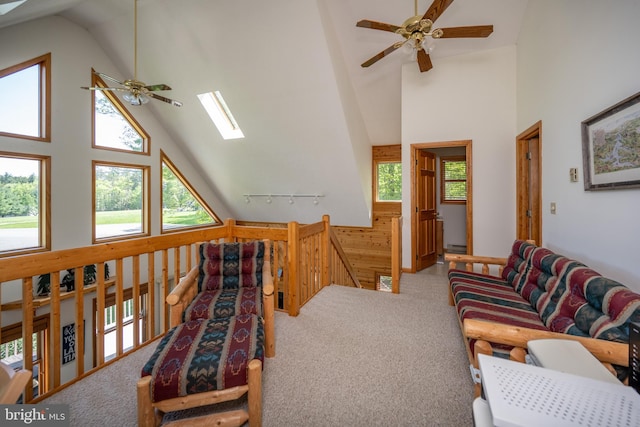 living room with a skylight, ceiling fan, carpet, high vaulted ceiling, and track lighting