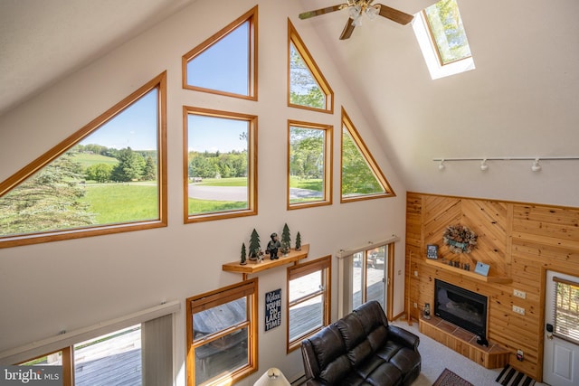 living room with high vaulted ceiling, carpet floors, a skylight, ceiling fan, and track lighting