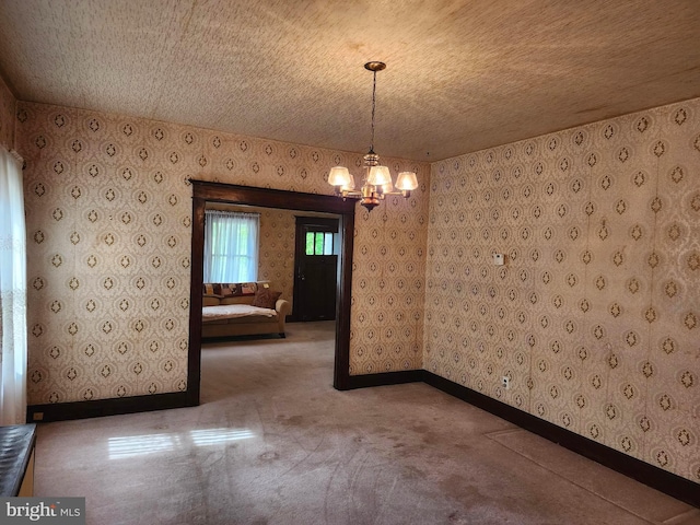 spare room with a chandelier, a textured ceiling, and carpet