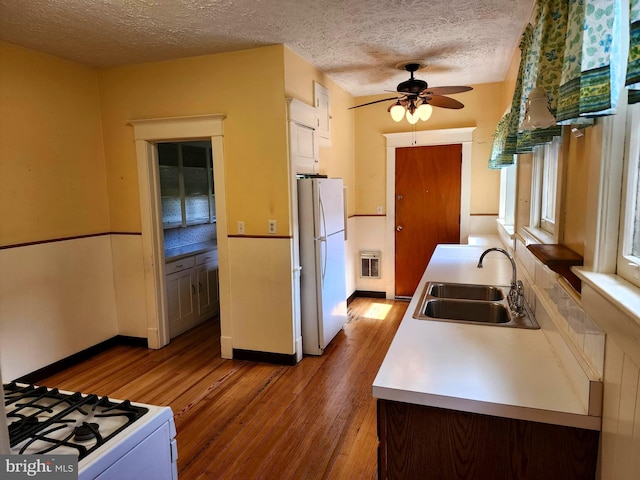 kitchen with a textured ceiling, white refrigerator, wood-type flooring, sink, and ceiling fan