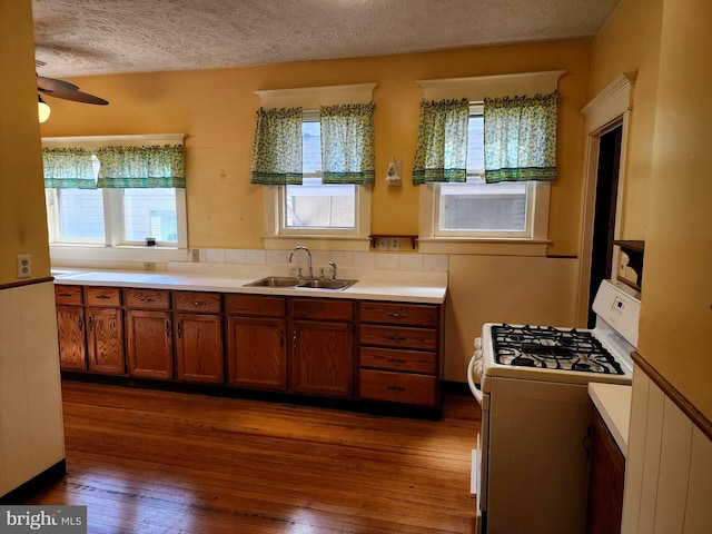 kitchen with sink, a textured ceiling, gas range gas stove, and hardwood / wood-style floors