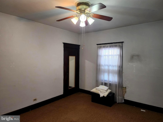 empty room featuring ceiling fan and dark carpet