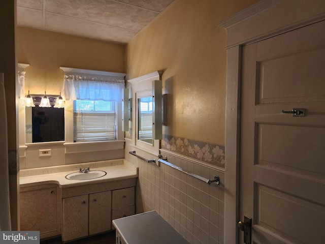 bathroom featuring tile walls and vanity with extensive cabinet space