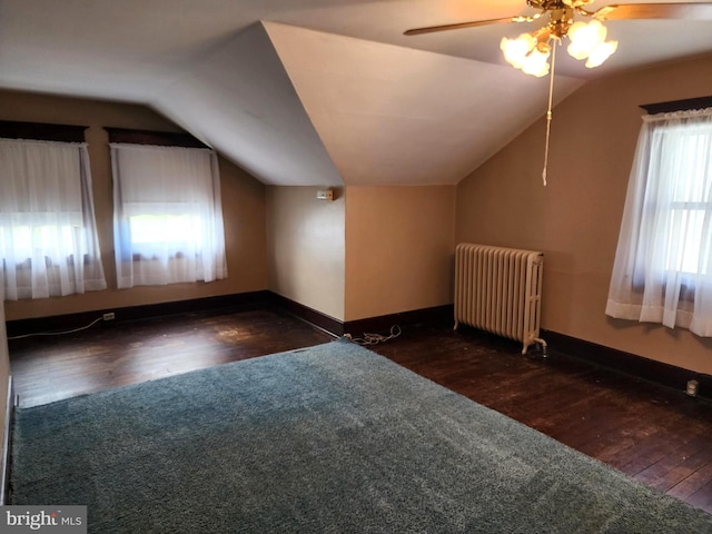 additional living space featuring dark hardwood / wood-style flooring, lofted ceiling, ceiling fan, and radiator heating unit