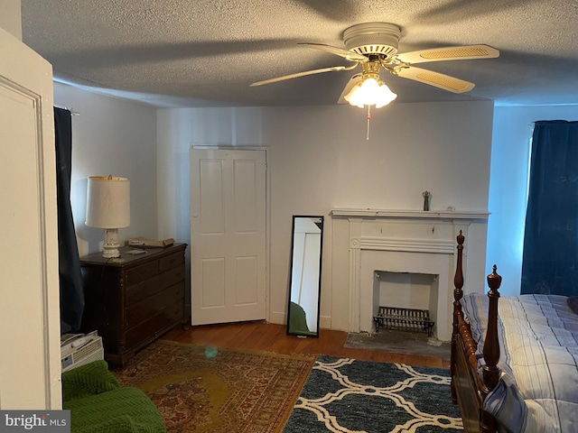 bedroom featuring ceiling fan, dark hardwood / wood-style flooring, and a textured ceiling