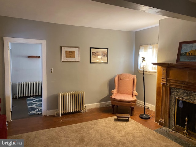 sitting room with a premium fireplace, radiator, and hardwood / wood-style floors