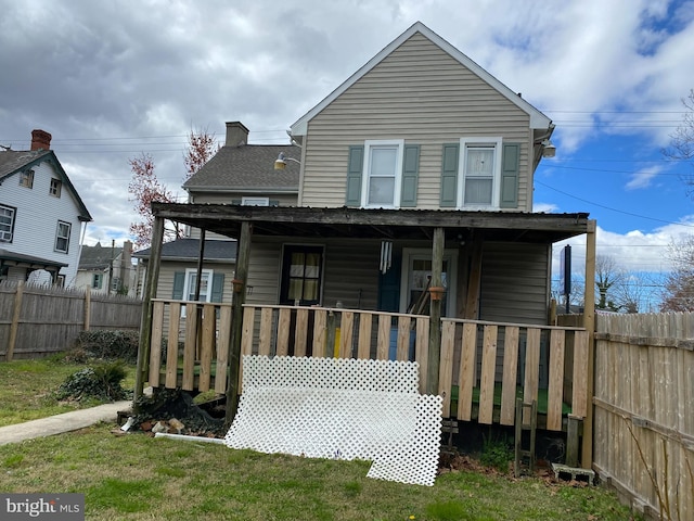 back of house featuring covered porch and a yard