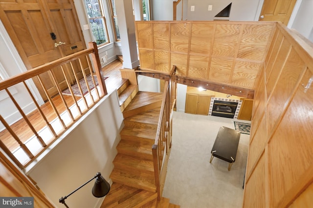 stairs with a tile fireplace and wood-type flooring