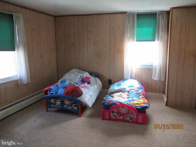 bedroom with baseboard heating, wooden walls, and carpet floors