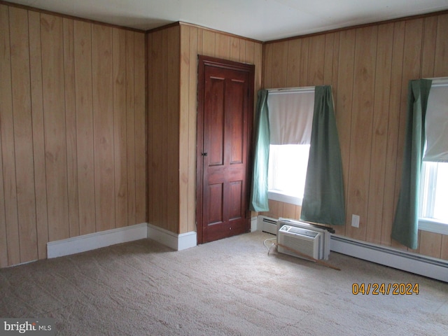 unfurnished room featuring carpet, baseboard heating, and wooden walls