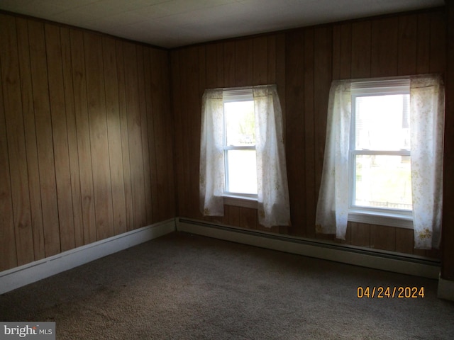 spare room with carpet floors, wooden walls, and a baseboard heating unit