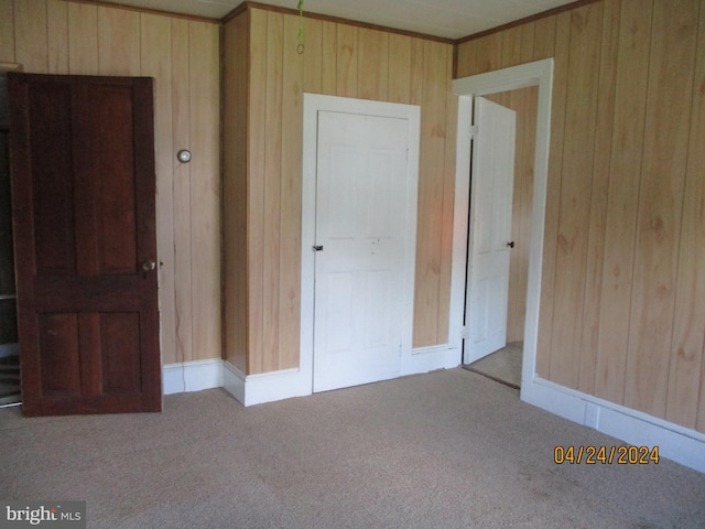 unfurnished bedroom with light carpet and wood walls