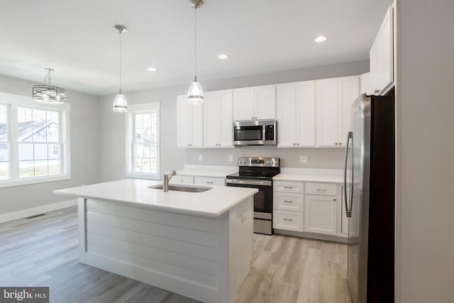 kitchen featuring pendant lighting, stainless steel appliances, sink, and white cabinets