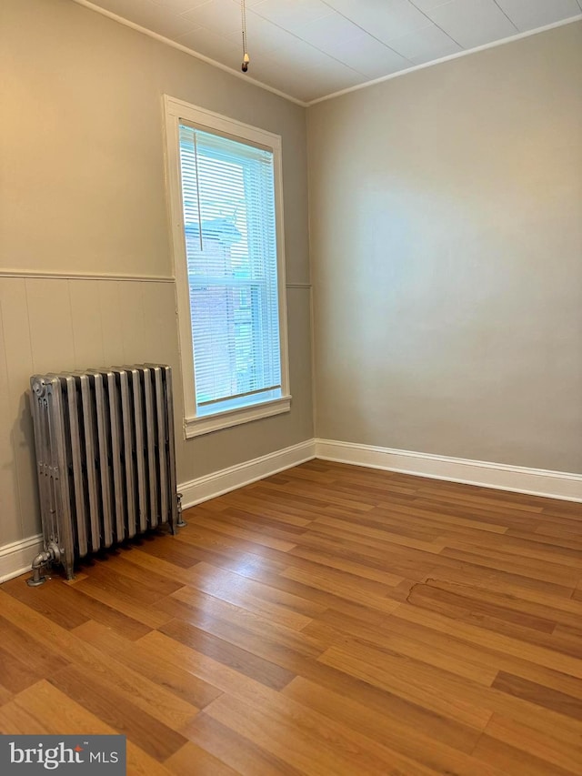 unfurnished room featuring hardwood / wood-style floors and radiator heating unit