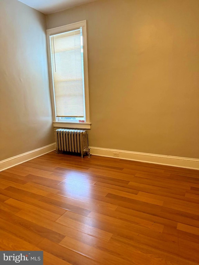 spare room with wood-type flooring and radiator