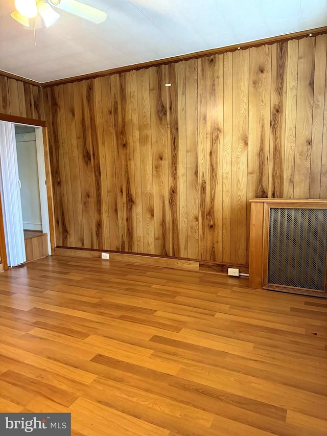 spare room with wood walls, ceiling fan, and light wood-type flooring