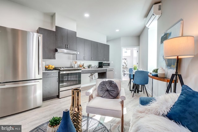 kitchen featuring appliances with stainless steel finishes, extractor fan, light wood-type flooring, and a wall mounted air conditioner