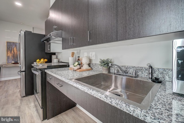 kitchen featuring stainless steel electric range, wall chimney range hood, light hardwood / wood-style floors, dark brown cabinets, and sink