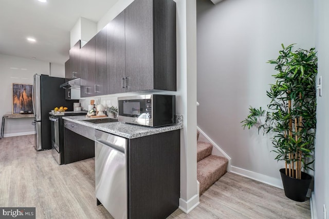 kitchen featuring light stone counters, light hardwood / wood-style floors, dark brown cabinets, appliances with stainless steel finishes, and sink