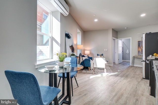 dining area featuring a wall mounted AC and light hardwood / wood-style flooring