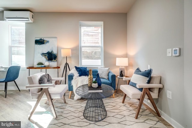 living room with an AC wall unit, plenty of natural light, and light wood-type flooring