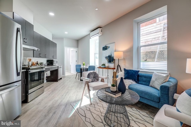 living room with a wealth of natural light, a wall unit AC, and light hardwood / wood-style flooring