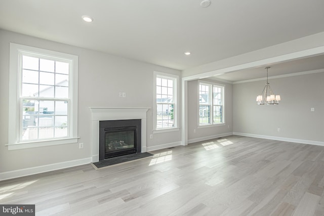 unfurnished living room with a notable chandelier, crown molding, and light wood-type flooring