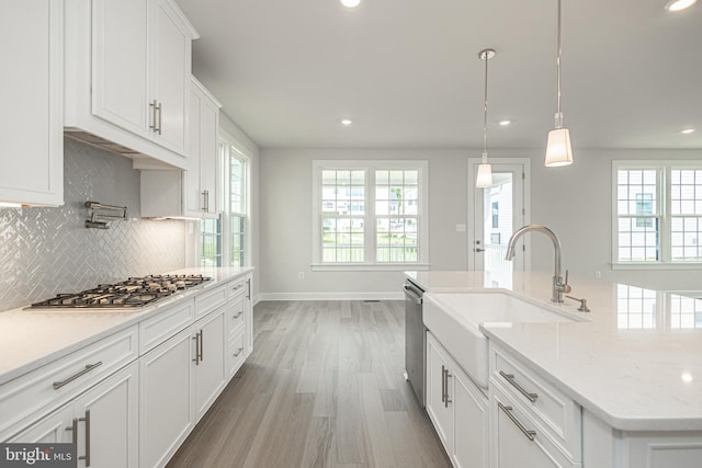 kitchen featuring white cabinets, tasteful backsplash, decorative light fixtures, stainless steel appliances, and wood-type flooring