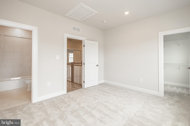 unfurnished bedroom with carpet flooring, a closet, a walk in closet, and ensuite bathroom