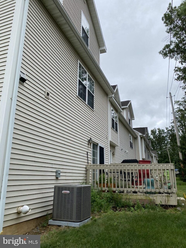 view of side of home with a lawn, central AC unit, and a deck