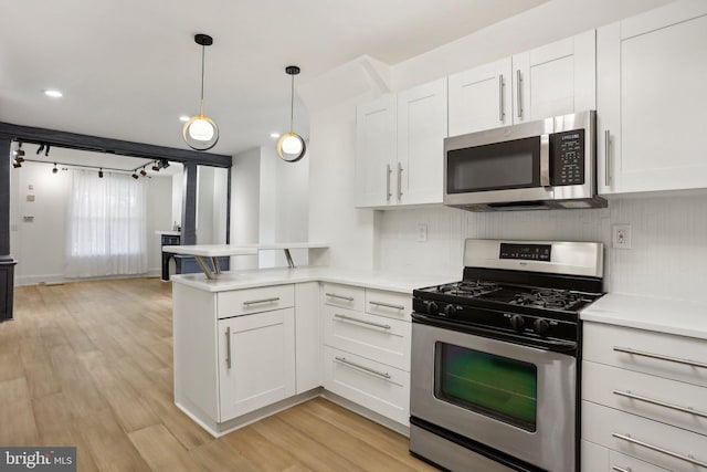 kitchen with backsplash, light hardwood / wood-style flooring, stainless steel appliances, white cabinets, and pendant lighting